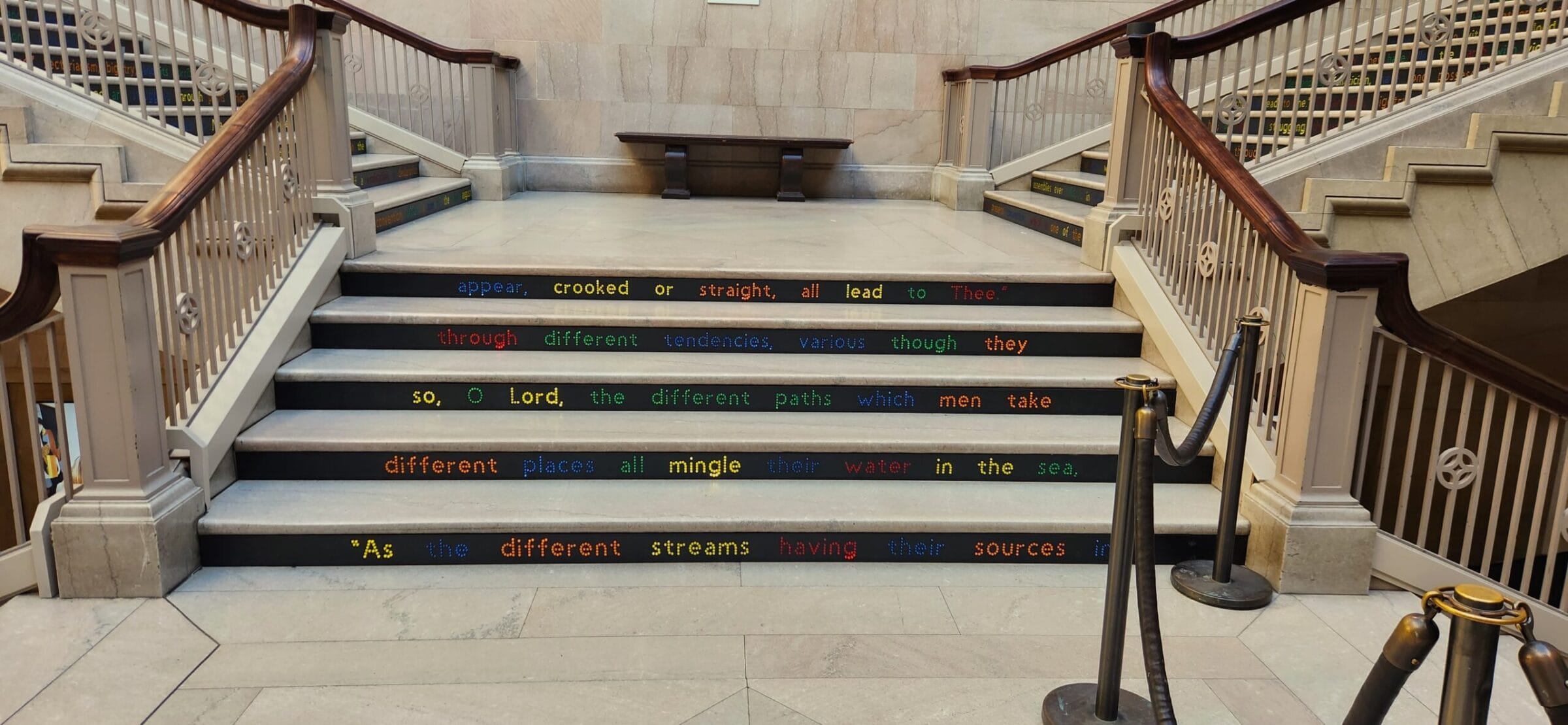 Grand staircase with colorful text on steps, quoting "As the different streams having their sources in".