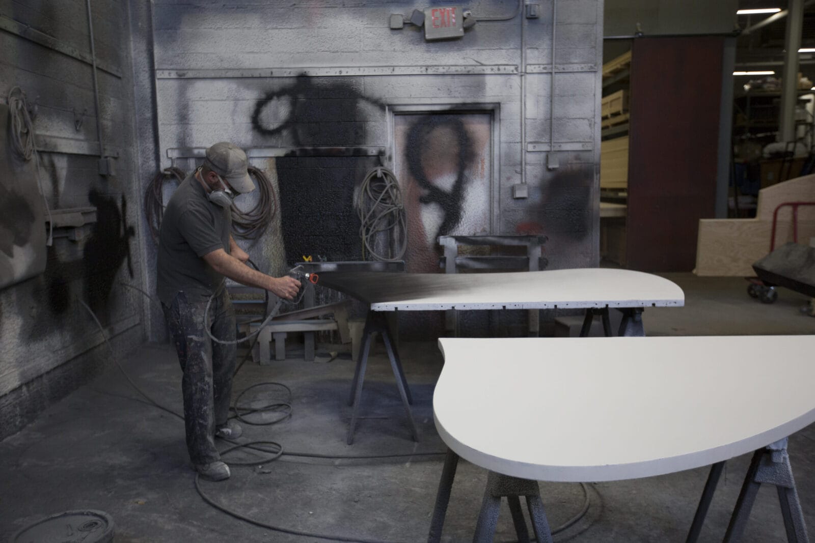 Man spray painting a curved surface in a workshop.