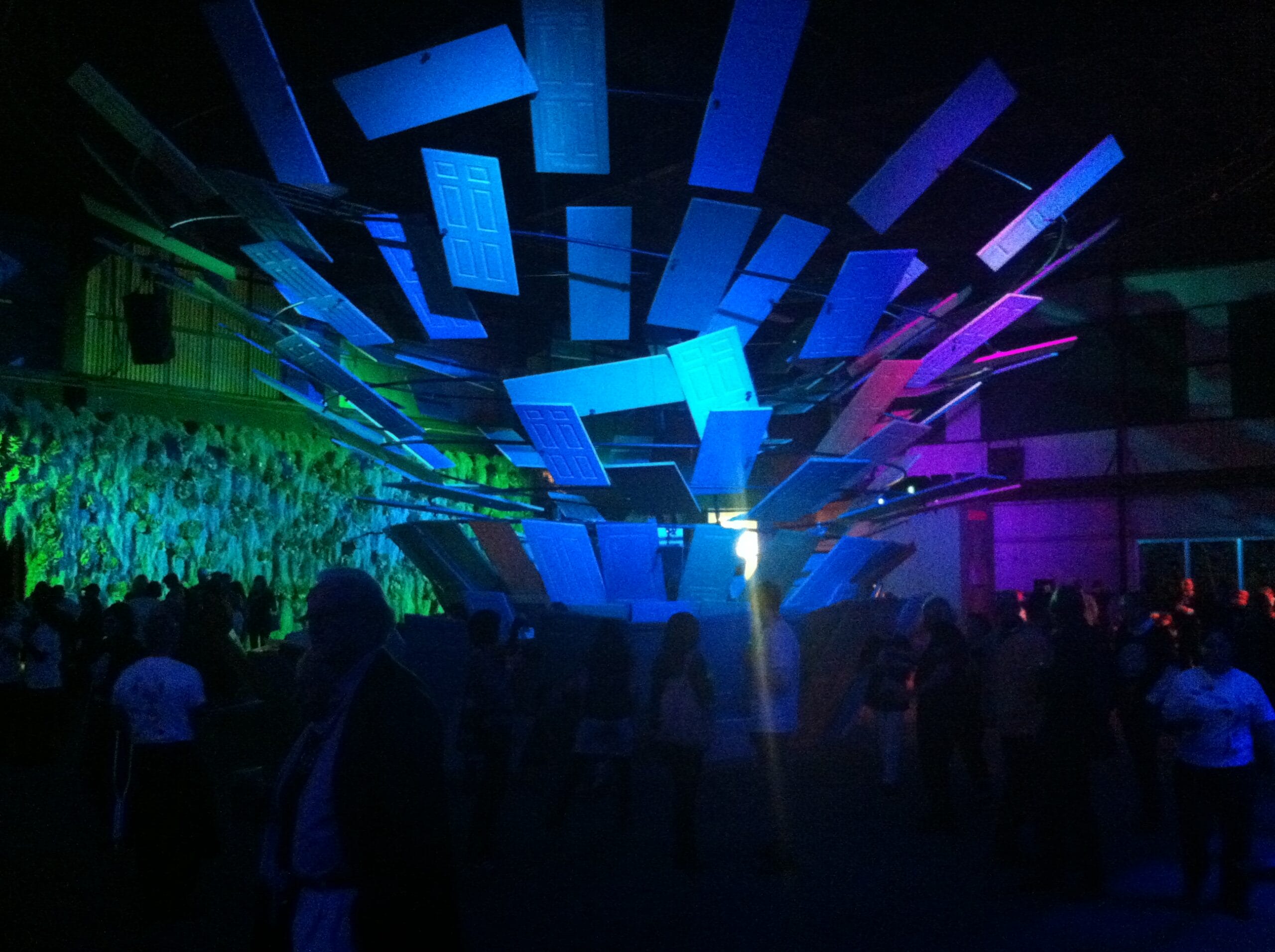 Ceiling installation of blue and purple doors over a crowd.