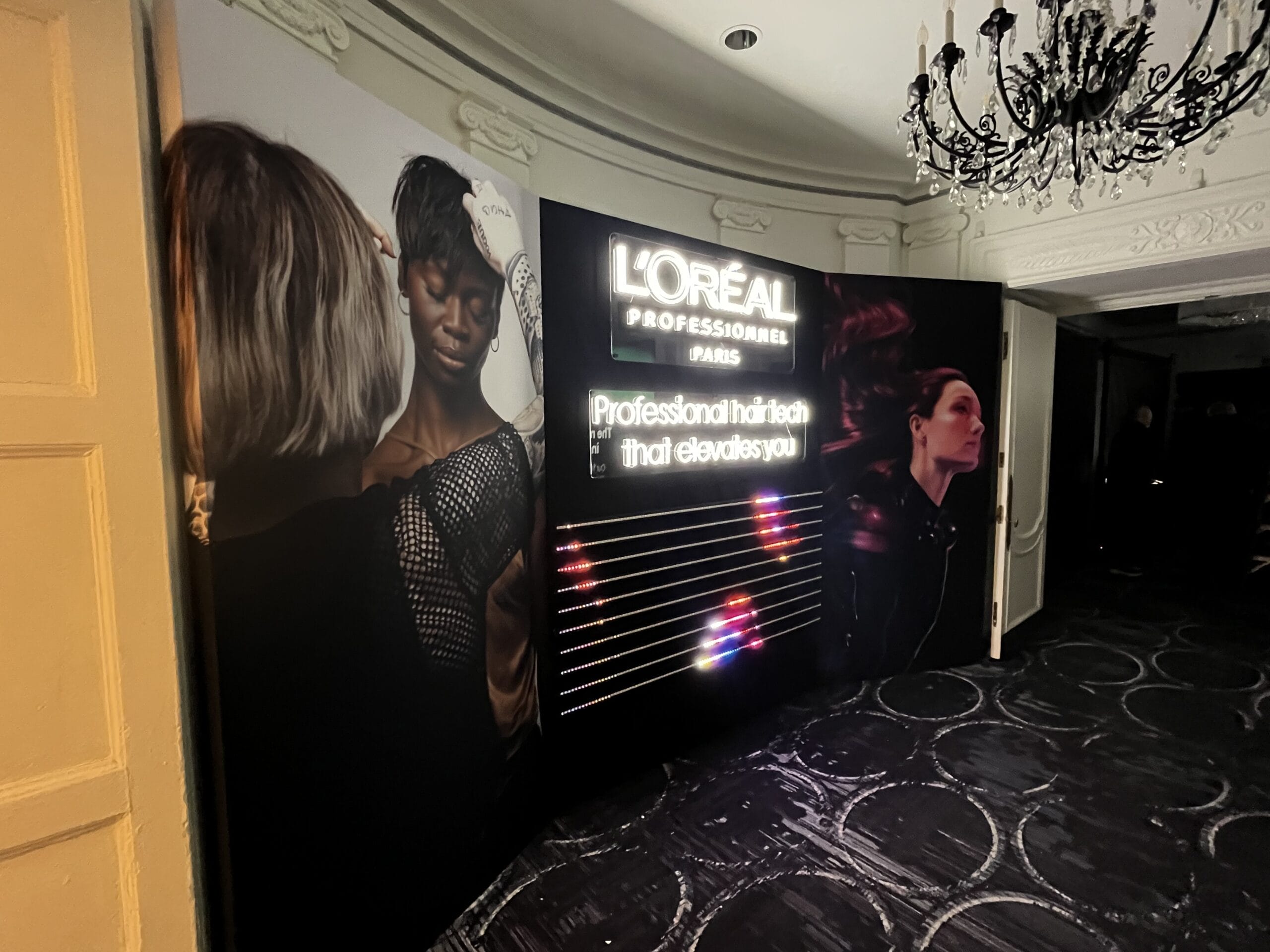 L'OrΓ©al Professional Paris display with models and neon lights.