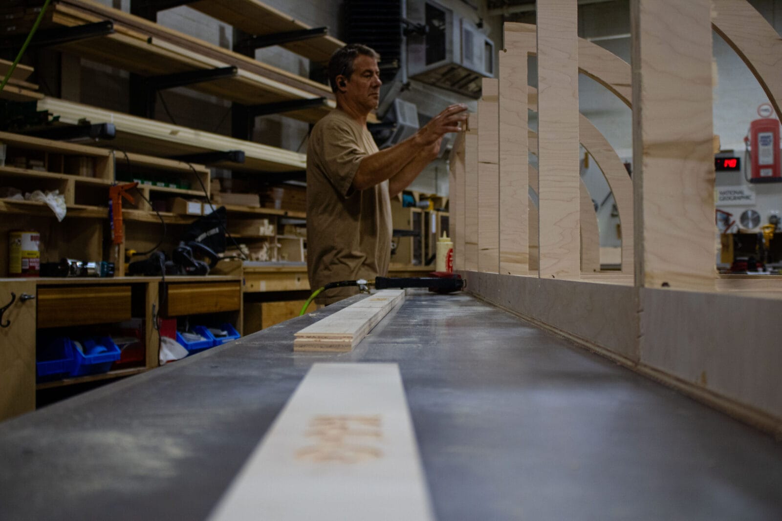 Woodworker assembling curved wooden panels in a workshop.