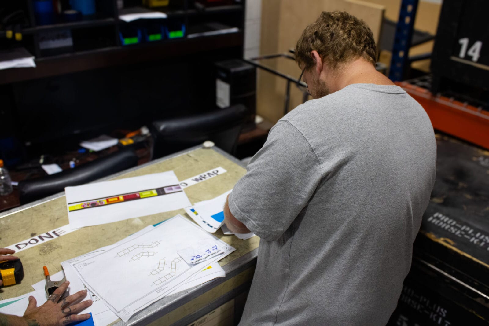 Man in gray shirt reviews plans and color samples on a table.