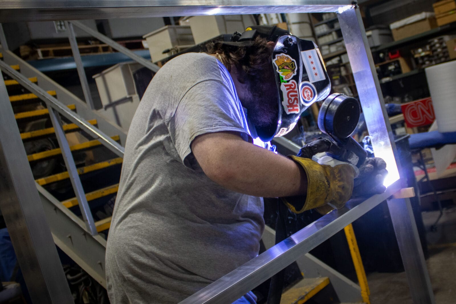 Welder in protective gear sparks metal frame in workshop.