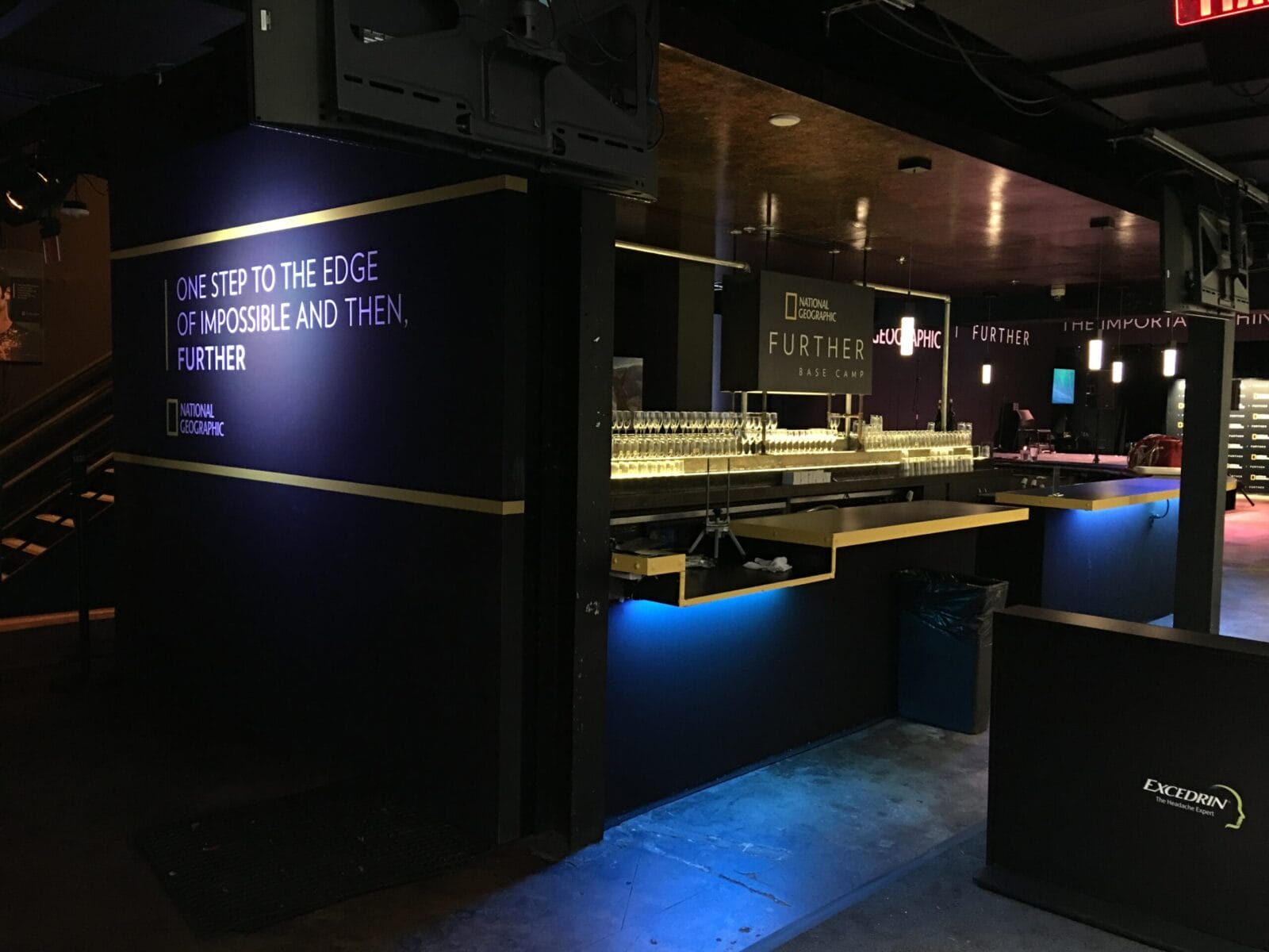 National Geographic event space with "FURTHER" branding and a bar.