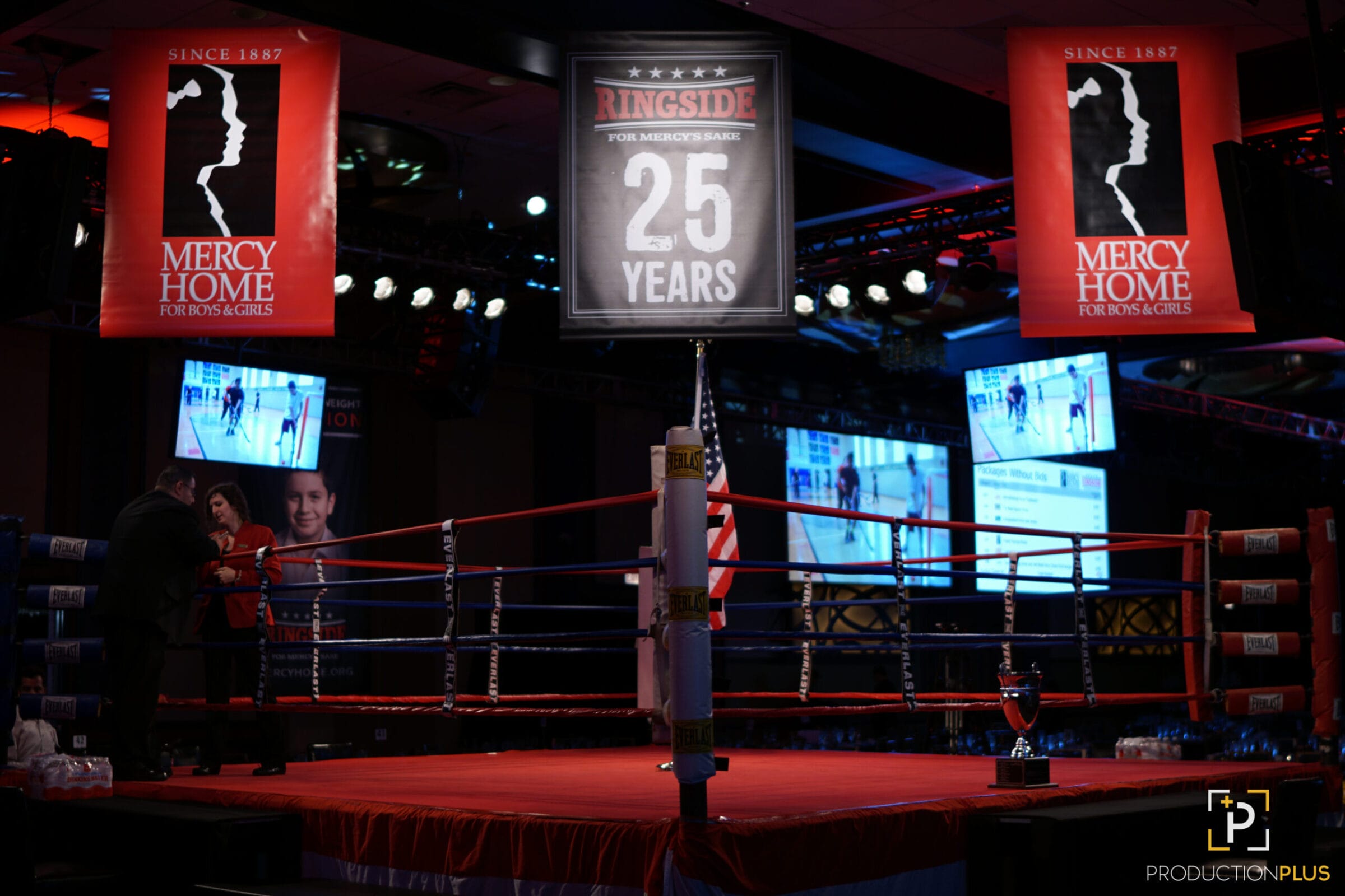 Boxing ring with "Mercy Home" banners and "25 Years" sign.